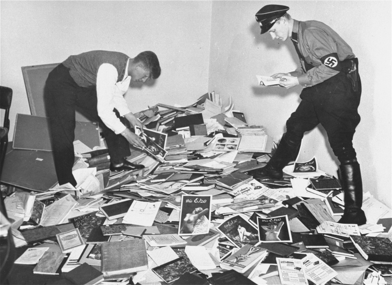Two young German men, one in an SS uniform, examine plundered books