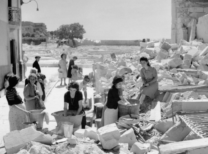 Maltese women washing clothes in the ruins of their homes